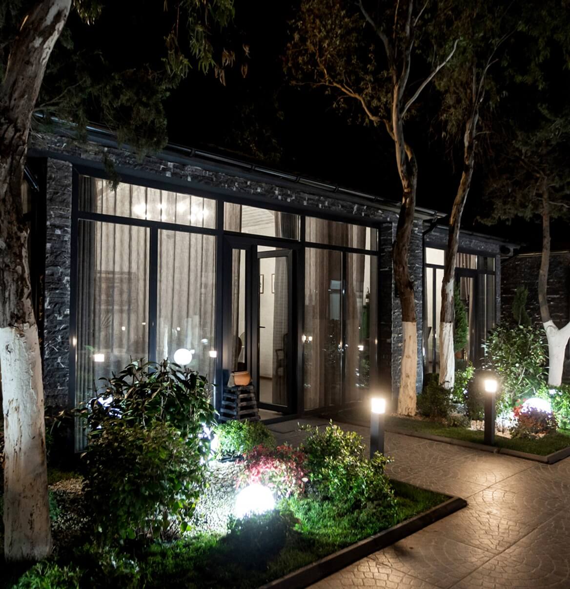 Modernes Gebäude mit LED-Außenbeleuchtung an Garten und Eingangsbereich bei Nacht