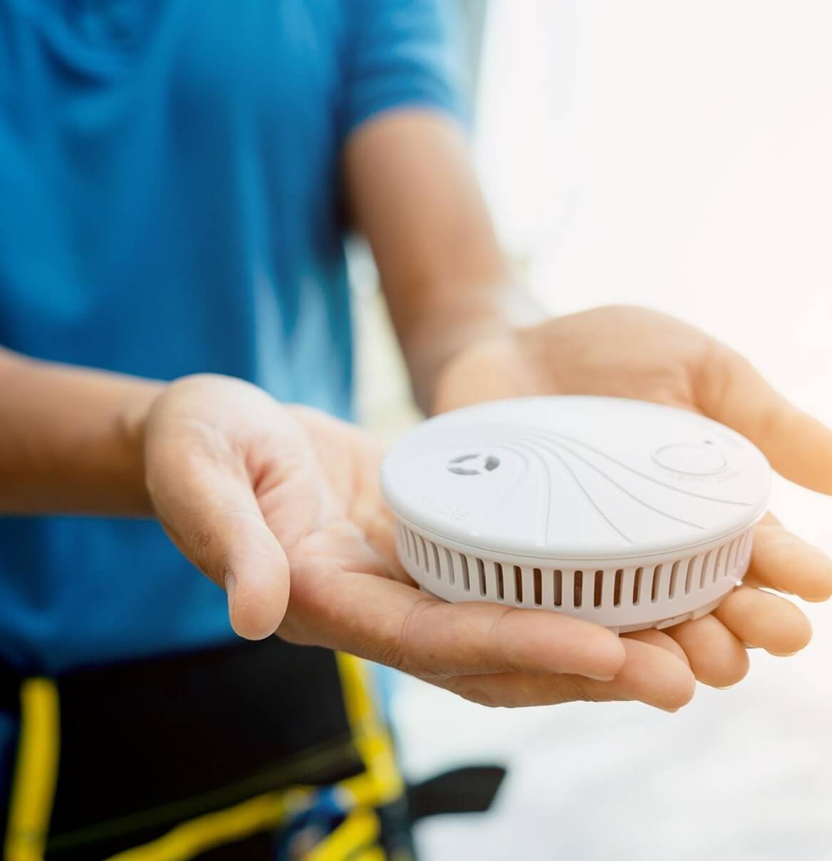 Elektriker hält Rauchwarnmelder in der Hand bereit zur Montage
