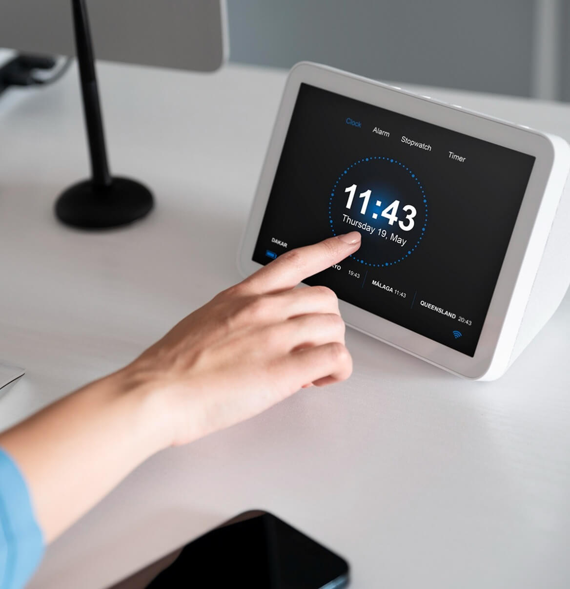 Finger tippt Uhrzeit auf Smart-Home-Touchscreen-Display auf Schreibtisch