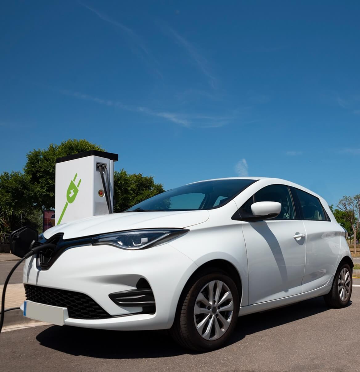 Weißes Elektroauto wird an öffentlicher Ladestation aufgeladen