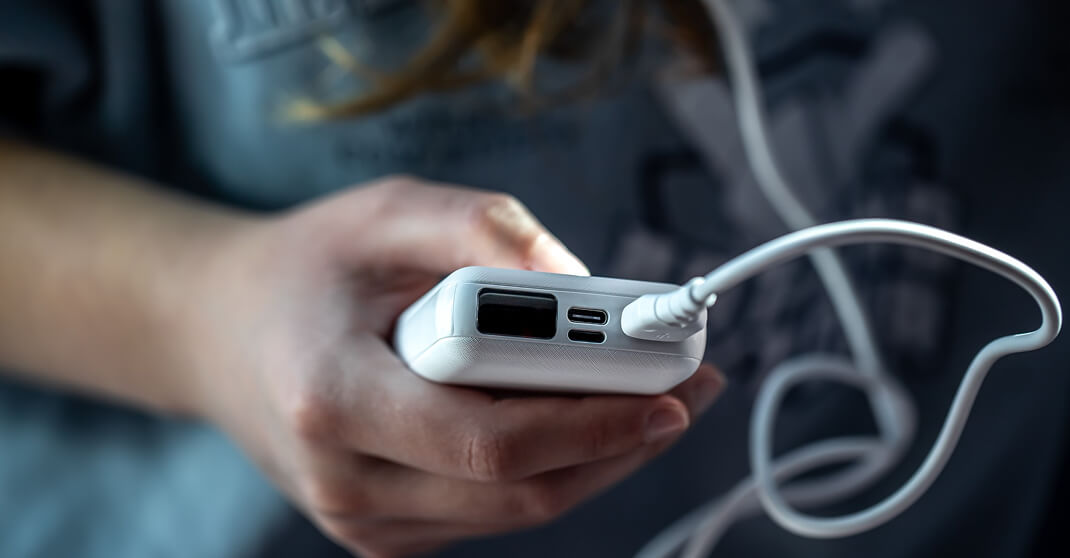 Elektriker in Warnweste prüft Sicherungskasten mit Tablet-Messgerät in Technikraum