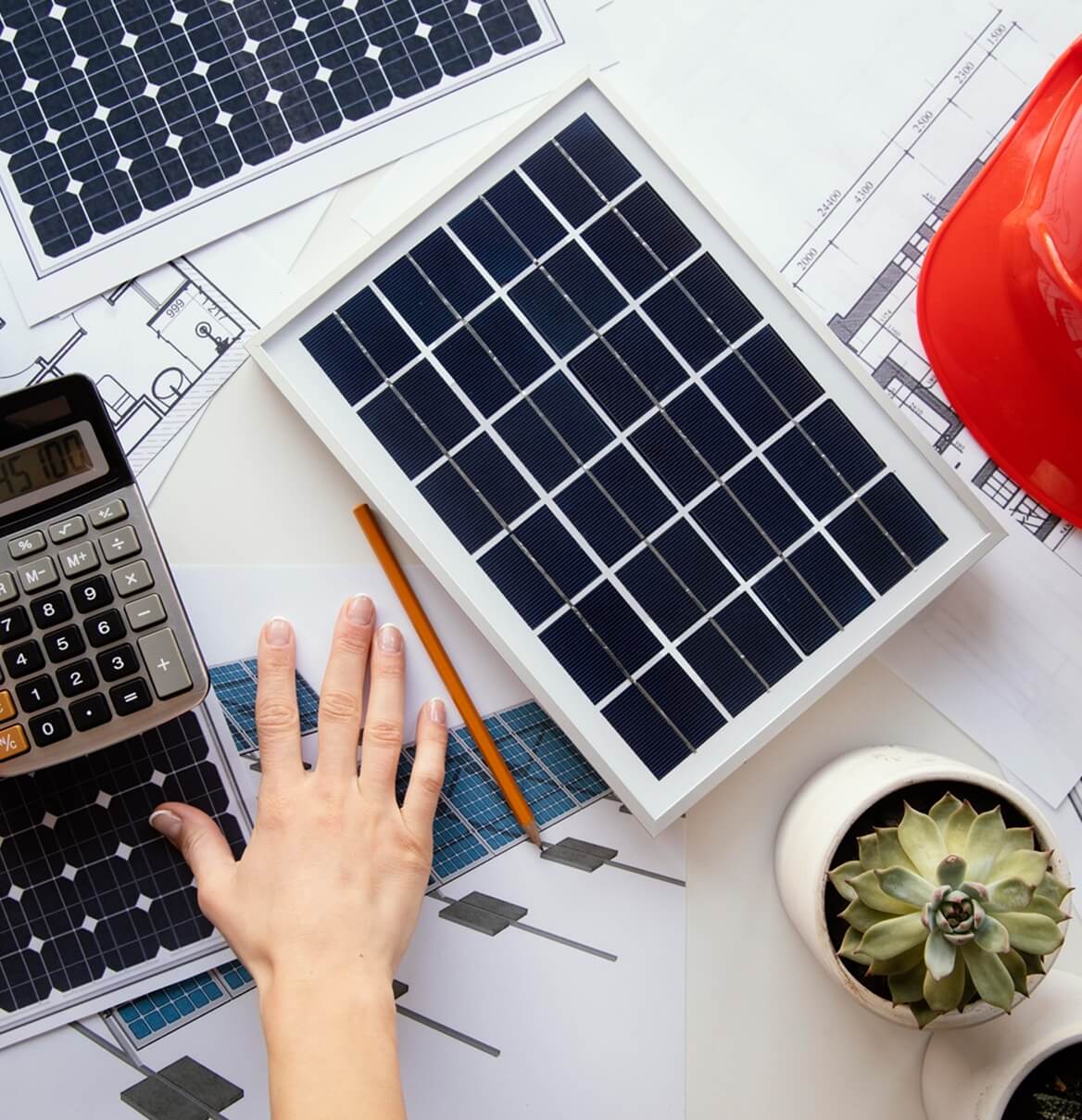 Schreibtisch mit Solarpanel-Muster, Taschenrechner und Bauplan für PV-Planung