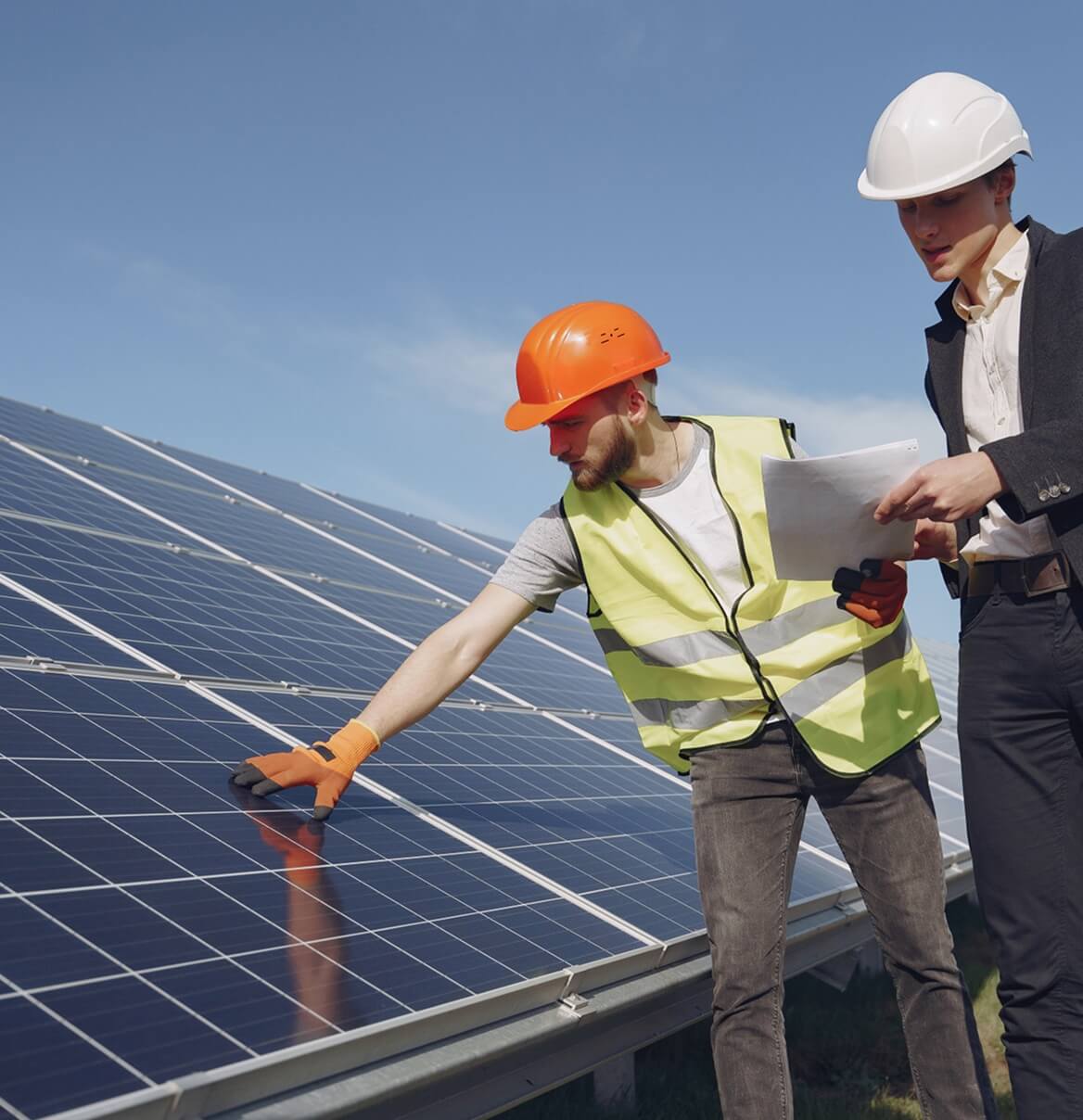 Zwei Solaranlagen-Techniker prüfen Photovoltaikmodul mit Unterlagen bei Inspektion