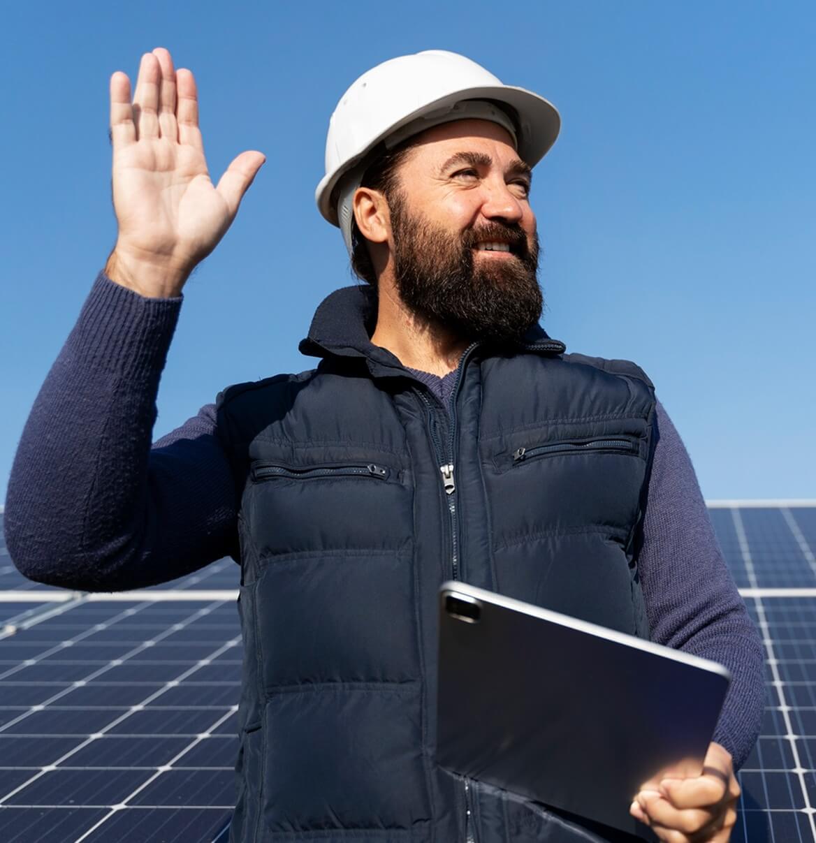 Photovoltaik-Techniker mit Schutzhelm und Tablet steht vor großer Solaranlage