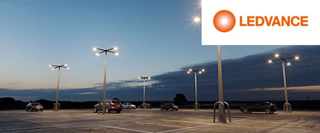 LED-Flutlichter auf hohen Masten beleuchten Parkplatz bei Abenddämmerung