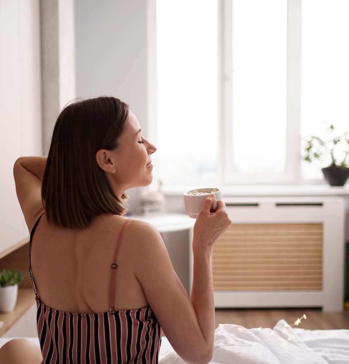 Person beginnt entspannt den Morgen im Smart-Home-Wohnraum mit Tageslicht