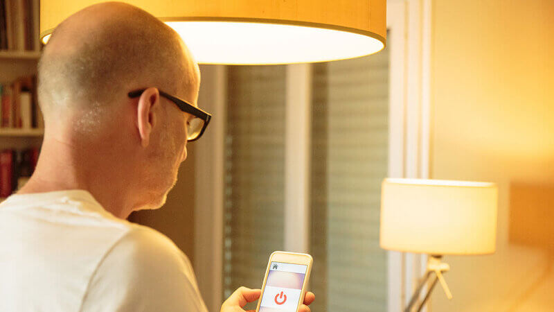 Mann steuert LED-Wohnraumbeleuchtung per Smartphone-App in Esszimmer